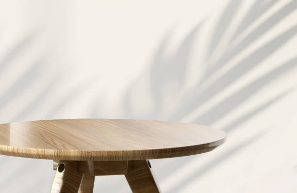 istock Modern round wooden side table with sunlight and monstera leaf shadow on beige wall background 1428282781