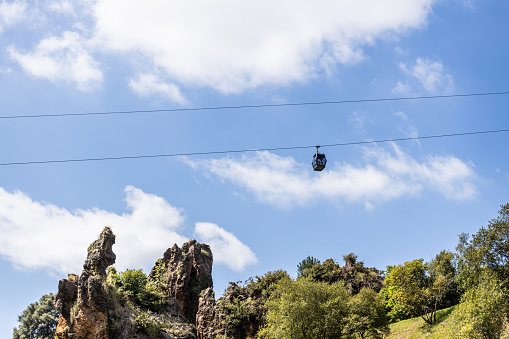 View from the bottom of the cable car under the blue sky on a beautiful summer day. In the background the green foliage of the trees completes the landscape.