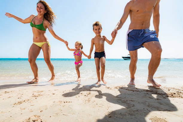 istock Carefree family holding hands while running on the beach. 1428289904
