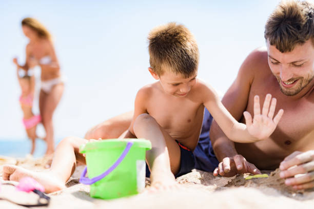 istock Happy father and son playing in sand on the beach. 1428290661