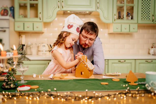istock a little girl in a chef's cap with dad makes a gingerbread house 1428293478
