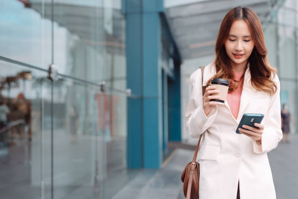 istock Beautiful asian female businesswoman use smartphone, Walk enjoy smiling while doing commuting in the modern city near office building outside 1428296763