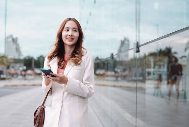istock Beautiful asian female businesswoman use smartphone, Walk enjoy smiling while doing commuting in the modern city near office building outside 1428296764