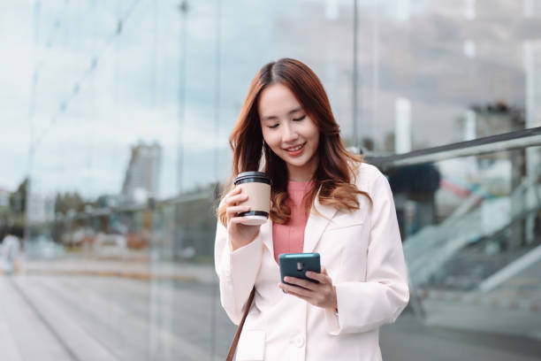 istock Beautiful asian female businesswoman use smartphone, Walk enjoy smiling while doing commuting in the modern city near office building outside 1428296767