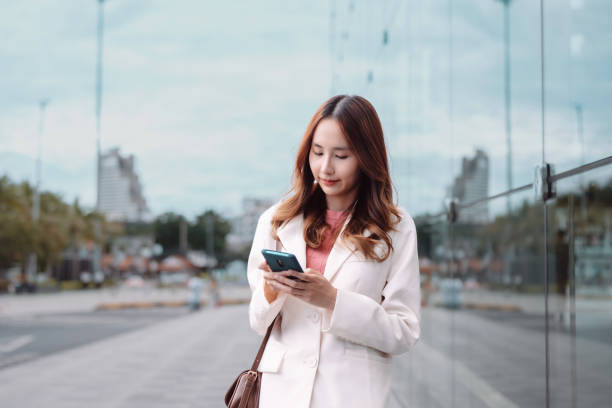istock Beautiful asian female businesswoman use smartphone, Walk enjoy smiling while doing commuting in the modern city near office building outside 1428296771