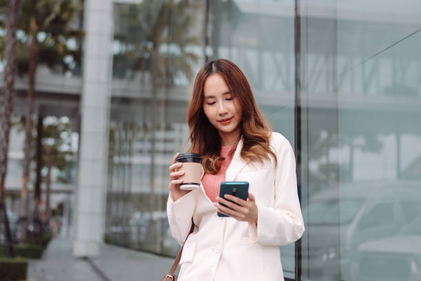 istock Beautiful asian female businesswoman use smartphone, Walk enjoy smiling while doing commuting in the modern city near office building outside 1428296773