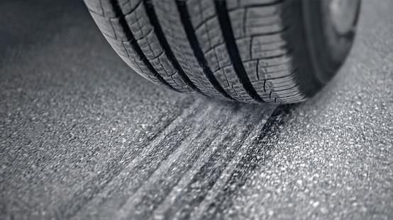 Close-up of tire of car driving on asphalt road.