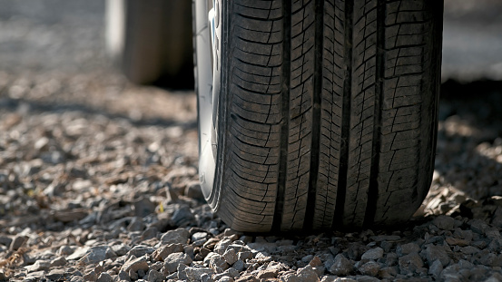 Close-up of tire of car driving on dirt road.