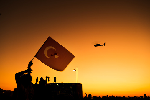 Primer plano de una bandera turca en la gente abarrotada con helicópteros gendarme en el cielo en el día de la libertad de Izmir en Izmir Konak Turquía photo