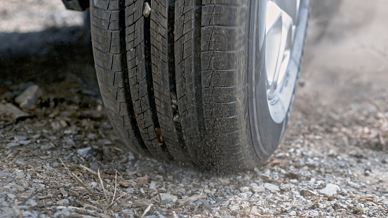 Close-up of tire of car driving on dirt road.