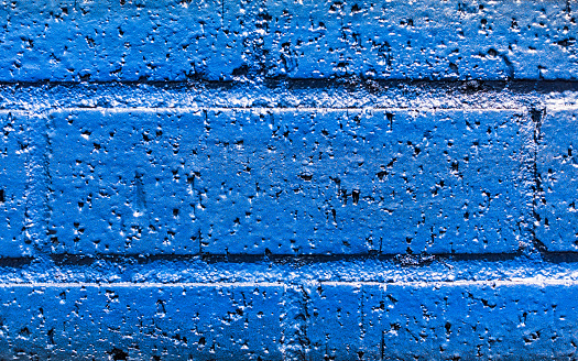 A close-up of a single brick in a wall, painted dark blue.