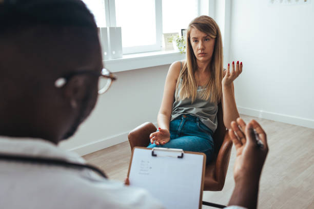 istock A young woman sits on a couch with her unrecognizable therapist. 1428302524