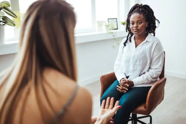 Photo of Psychologist listening to her patient and writing down notes