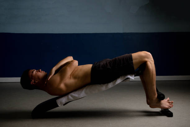 Shirtless 19 year old teenage boy soing situps on an exercise bench