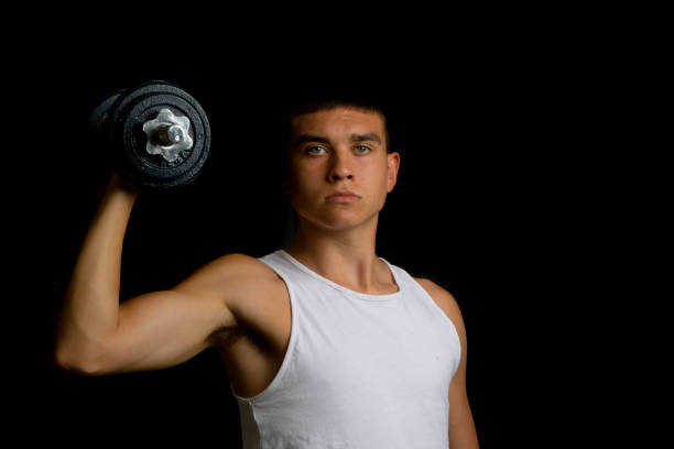 19 year old teenage boy wearing a tank top using a dumbbells