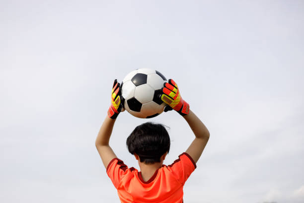 A football player who is a goalkeeper receives the ball.