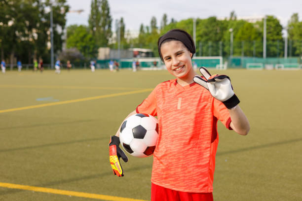 Soccer girl Girl with goalkeeper gloves holding the ball looking at the camera teen goalie stock pictures, royalty-free photos & images