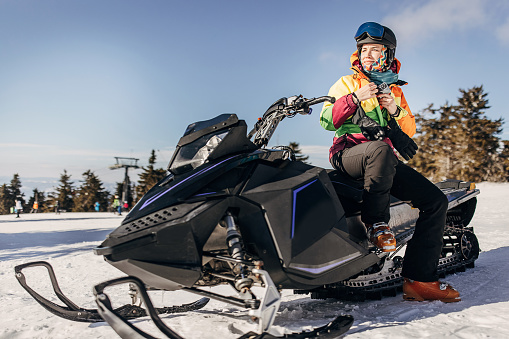 One woman, female sitting on snowmobile on the hill on a snowcapped mountain.