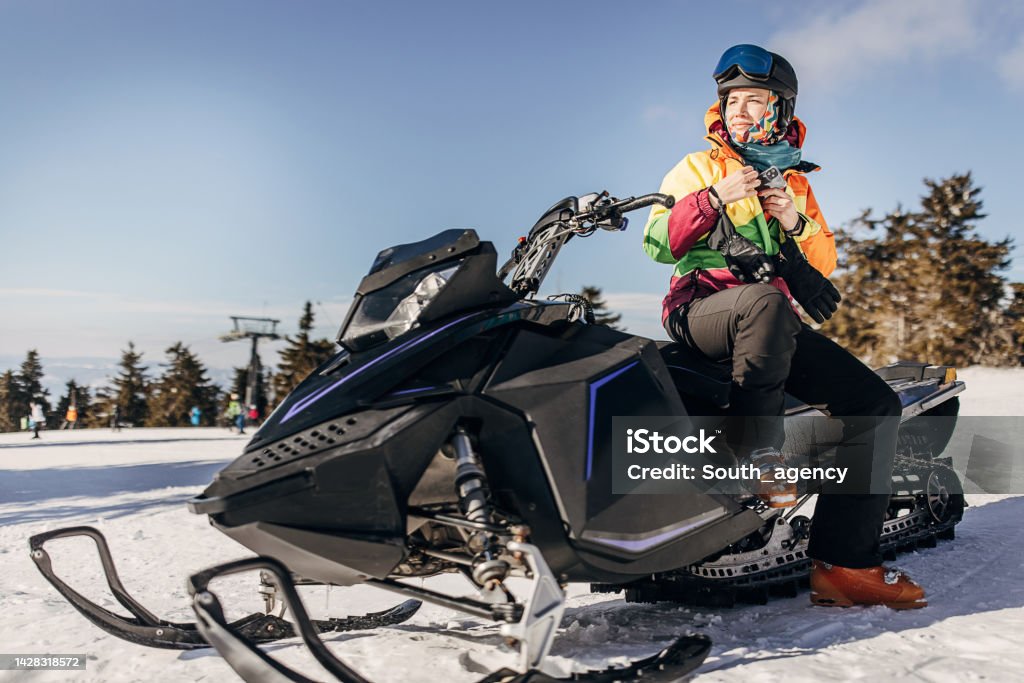 Woman sitting on snowmobile One woman, female sitting on snowmobile on the hill on a snowcapped mountain. Snowmobile Stock Photo