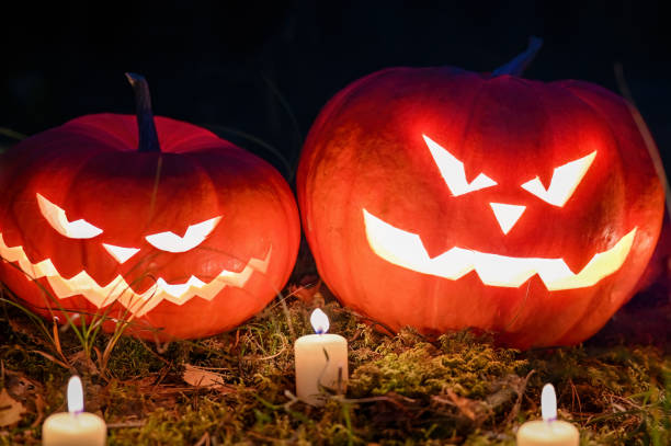 istock Scary jack o lanterns in spooky forest with ghost lights. pumpkin head for halloween with burning candles. 1428321116