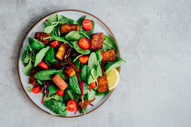 istock Top view healthy salad with roasted tempeh, cherry tomato, beetroot straws, spinash and lettuce leaves on plate. Tempeh is fermented soy bean. Plant based protein. Healthy Cooking and eating. Go vegan 1428325550