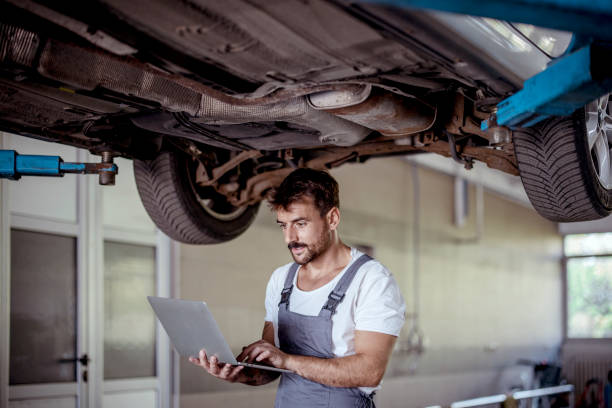 istock Car Mechanic Under Vehicle using laptop 1428330699