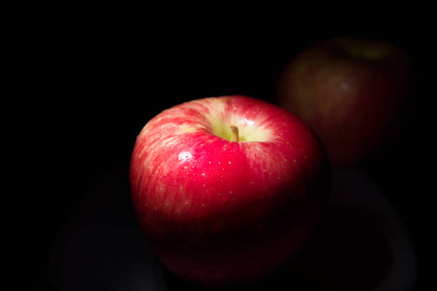 istock fresh red apple On a black background with water droplets, lights are falling with space for text. 1428331813