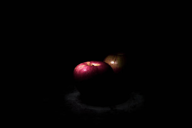 two fresh red apples On a black background with water droplets, lights are falling with space for text.
