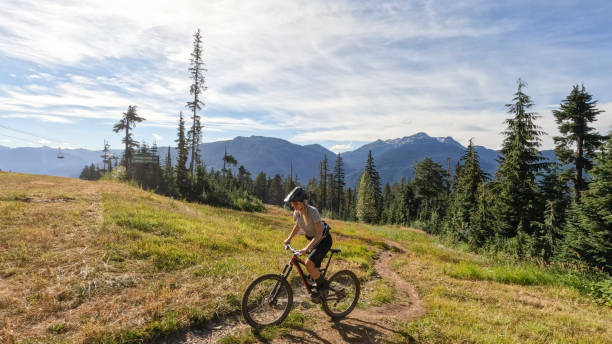 istock Young woman mountain biking along narrow pathway 1428333465