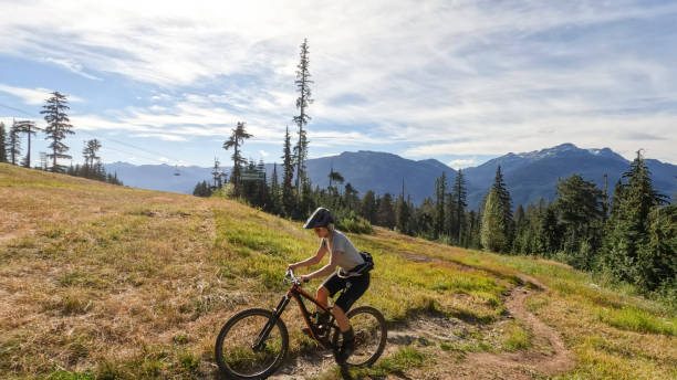istock Young woman mountain biking along narrow pathway 1428333477