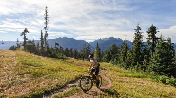 istock Young woman mountain biking along narrow pathway 1428333571