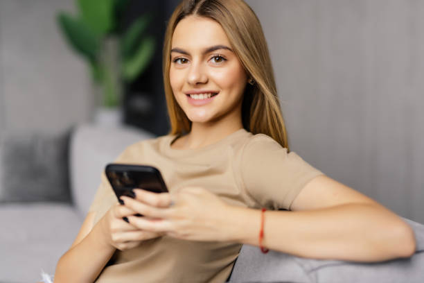 Calm attractive woman sit on sofa using smartphone, close up. Generation and modern tech everyday usage for fun, making distant order, communication remotely, web surfing, internet connection concept
