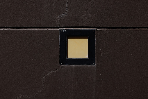 Small electric light built in to a brown concrete wall.