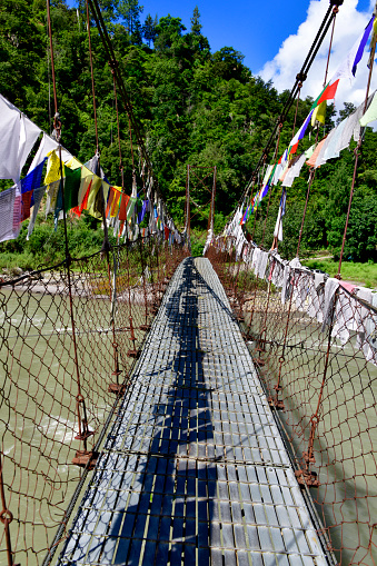 Yebisa, Punakha district, Bhutan: walking on the suspension bridge over the Mo Chu river, view from Kabisa Gewog, towards Chuuboog Gewog - prayer flags along the bridge, Mochu Rafting Point.