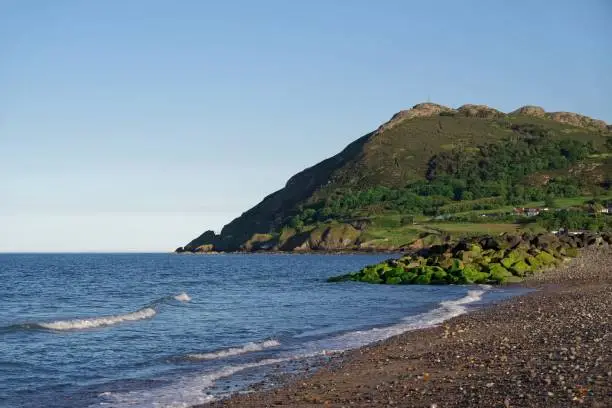 Seascape with calm Irish Sea, pebble beach and rocks on sunny summer day in Bray, Co. Wicklow, Ireland. Famous Bray Head mountain in the background.
