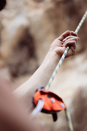 Close up shot of a man's hands operating a rock climbing assisted belaying device.