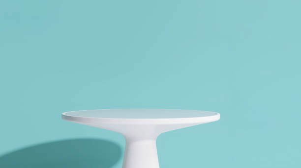 Modern and minimal white smooth round podium side table in sunlight on pastel turquoise blue wall background