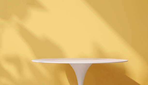 istock Modern and minimal white smooth round podium side table with sunlight and leaf shadow on pastel yellow wall background 1428360250