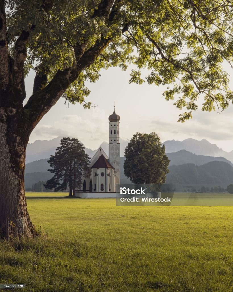 Vertical shot of St. Coloman church in a harmonic natural space in Schwangau, Germany A vertical shot of St. Coloman church in a harmonic natural space in Schwangau, Germany Architecture Stock Photo