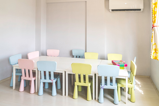 Kindergarten Classroom With Table, Multi Color Chairs and Toys.