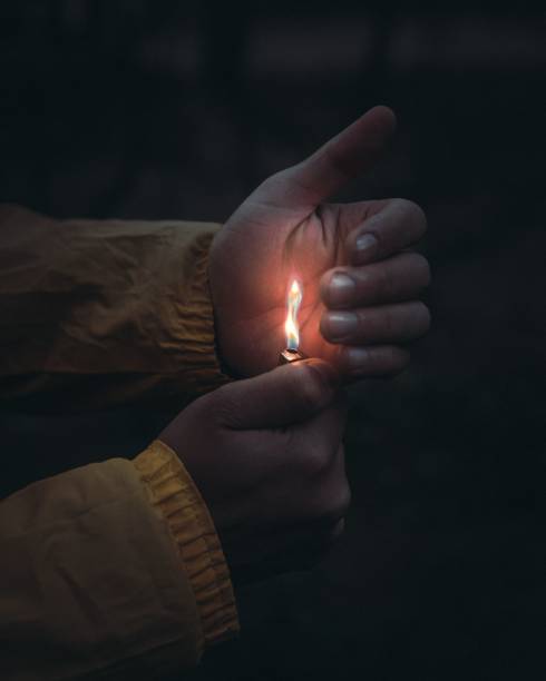 istock Closeup vertical shot of man's hands covering the lighter 1428366543