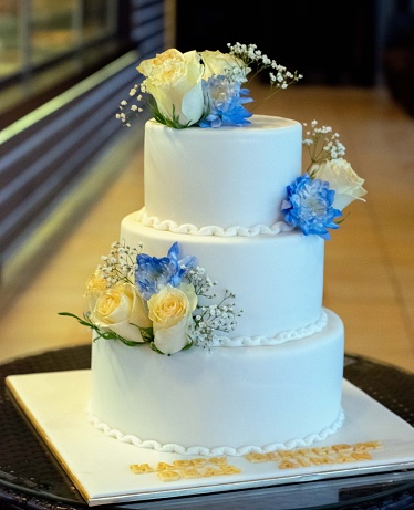 A vertical shot of a 3 tier beautiful floral cake