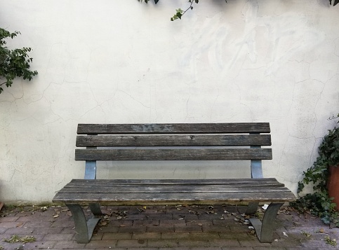A wooden bench near a white wall