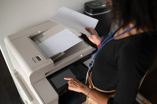 making copies. Woman standing near the xerox in the office