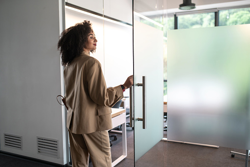 In the office. Confident and determined businesswoman entering a modern office with glass doors