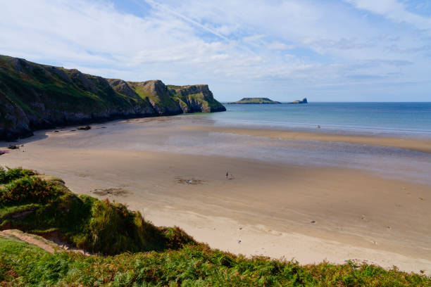 Almost deserted Rhossili beach at low tide. Virtually deserted beach at low tide below the steep cliffs of Rhossili Bay. rhossili bay stock pictures, royalty-free photos & images