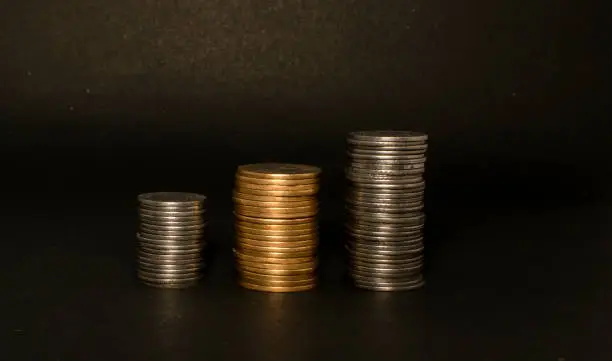 Indian rupees coins are stacked on a black paper surface, finance, investment and business concept