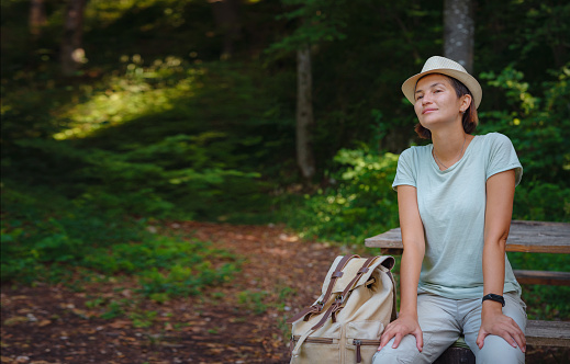 travel to summer Europe young asian woman. observation point above the village of Roggenburg, Switzerland. hike in summer forest, having a break