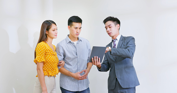 asian male real estate agent using tablet to show a family the house