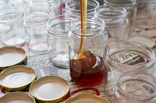 Filling of glass jars of honey on a table